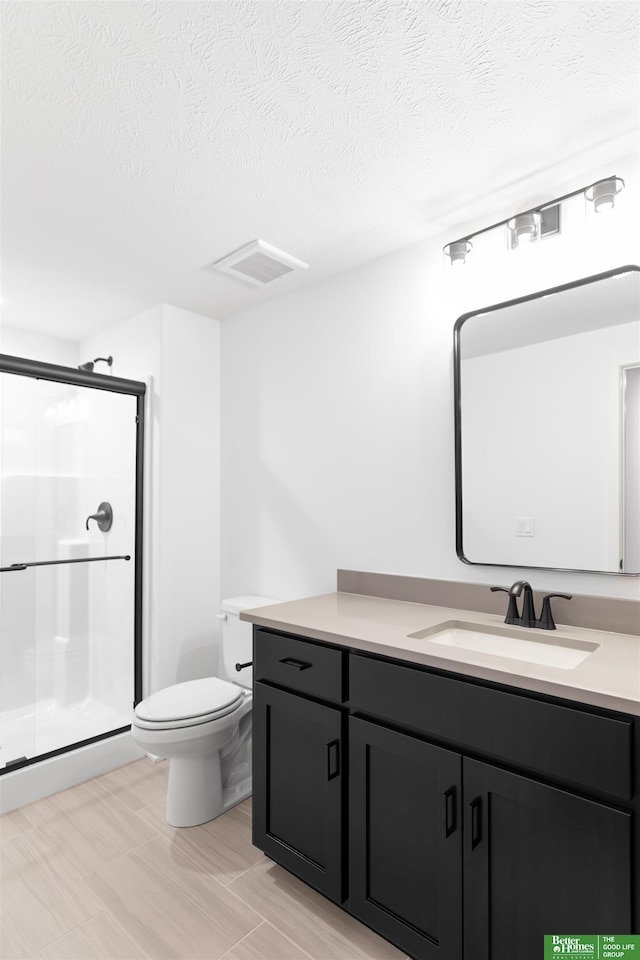 bathroom featuring vanity, toilet, a textured ceiling, and a shower with shower door