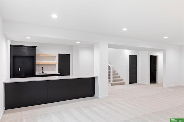 kitchen featuring light colored carpet, kitchen peninsula, sink, and backsplash