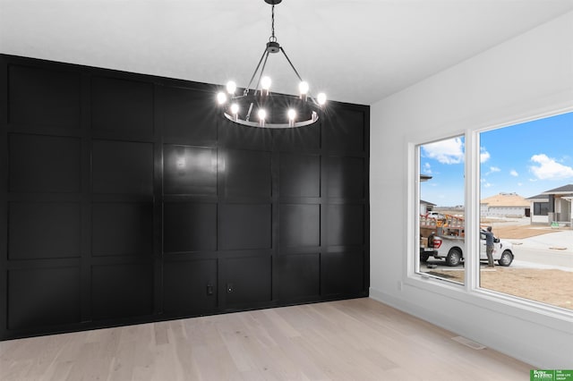 unfurnished dining area with a chandelier and light hardwood / wood-style floors