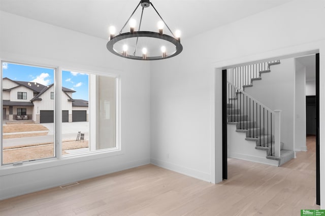 unfurnished dining area featuring light hardwood / wood-style flooring and a notable chandelier