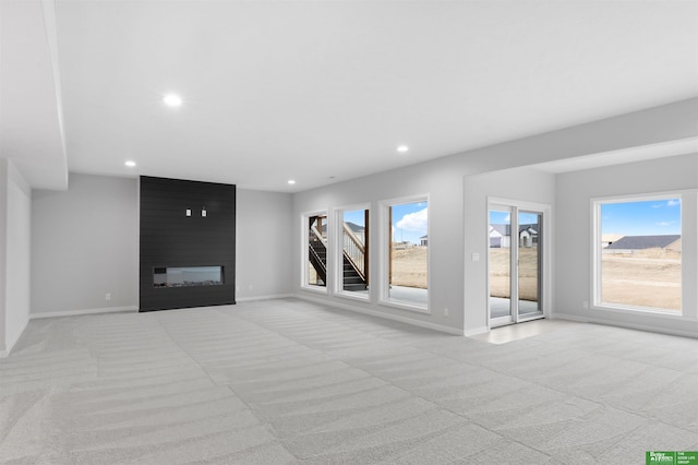 unfurnished room with light carpet and a fireplace