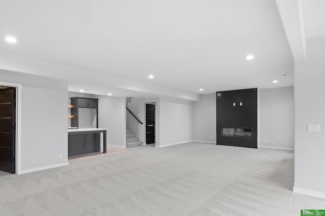 unfurnished living room featuring a large fireplace and light colored carpet