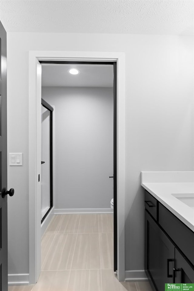 bathroom with a shower with door, vanity, a textured ceiling, and toilet