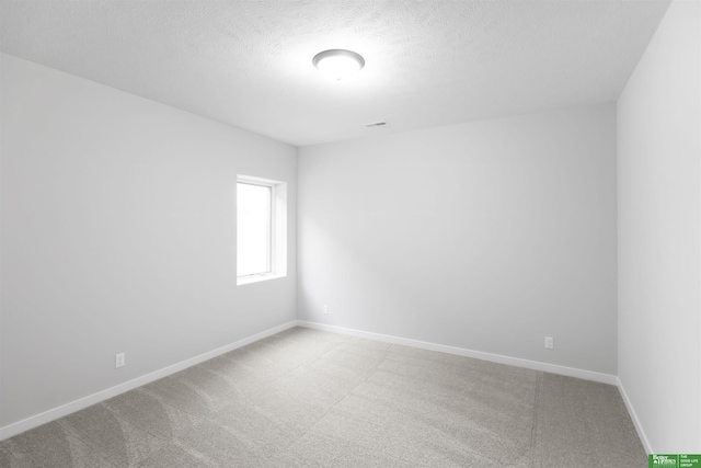 spare room featuring carpet flooring and a textured ceiling