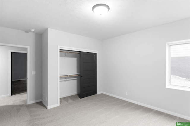 unfurnished bedroom featuring light colored carpet and a closet