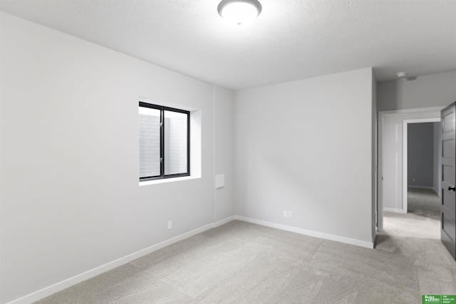 empty room featuring light colored carpet and a textured ceiling