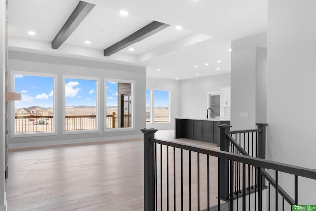 hall with sink, light hardwood / wood-style flooring, and beamed ceiling