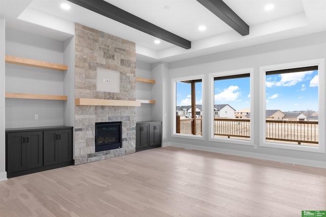 unfurnished living room with beamed ceiling, light wood-type flooring, and a fireplace