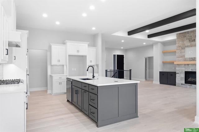 kitchen with sink, gray cabinetry, white cabinetry, a fireplace, and a kitchen island with sink