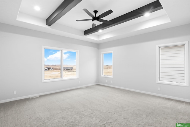 carpeted spare room featuring a raised ceiling, ceiling fan, and beam ceiling