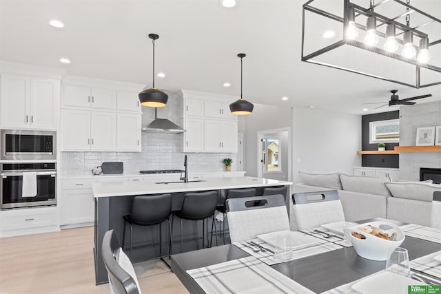 kitchen with white cabinetry, decorative light fixtures, stainless steel appliances, and a kitchen bar