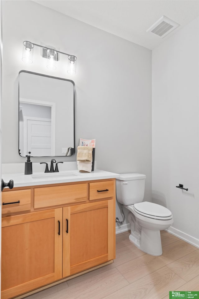 bathroom featuring vanity, hardwood / wood-style flooring, and toilet