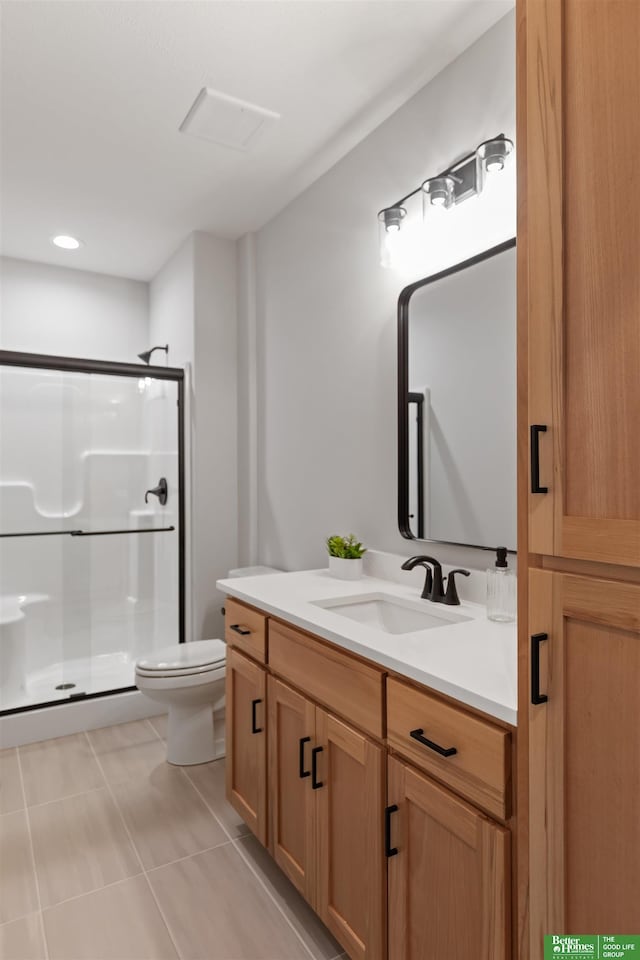 bathroom with vanity, toilet, a shower with shower door, and tile patterned flooring