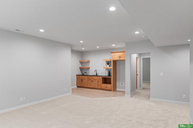 unfurnished living room with sink and light colored carpet