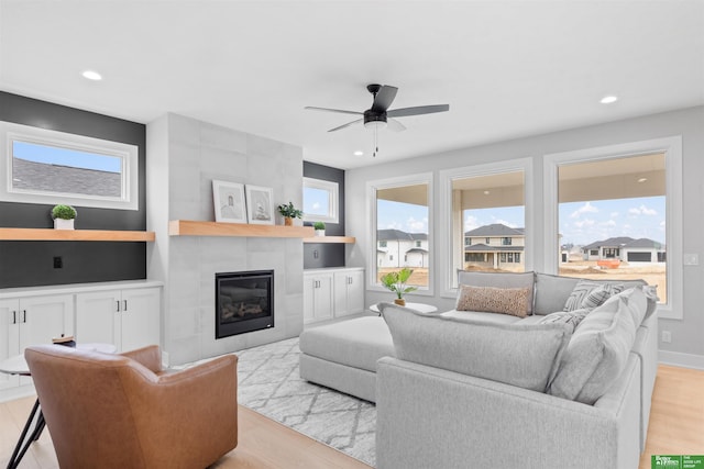 living room with ceiling fan, light hardwood / wood-style floors, and a tile fireplace