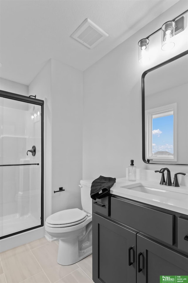 bathroom featuring tile patterned floors, vanity, toilet, and a shower with door