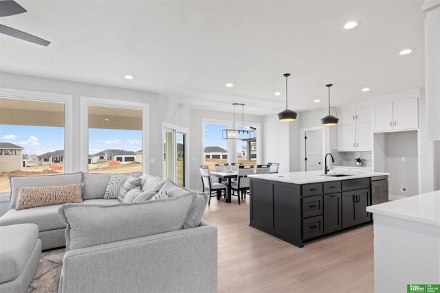 kitchen featuring sink, white cabinetry, hanging light fixtures, a center island with sink, and stainless steel dishwasher