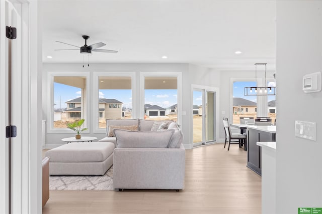 living room with ceiling fan with notable chandelier and light hardwood / wood-style floors