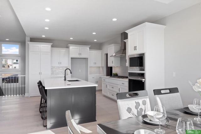 kitchen featuring wall chimney exhaust hood, stainless steel appliances, sink, and white cabinets