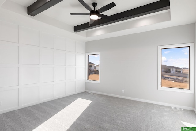 carpeted spare room featuring ceiling fan and beamed ceiling