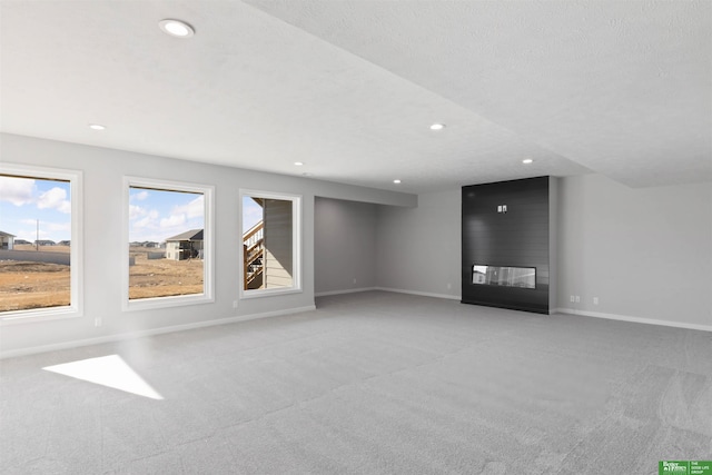 unfurnished living room with light carpet, a fireplace, and a textured ceiling