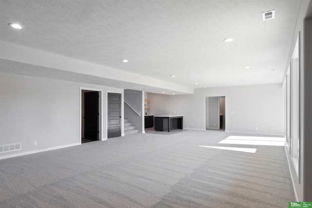 interior space featuring light carpet and a textured ceiling