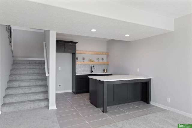 kitchen with sink, a kitchen breakfast bar, kitchen peninsula, light colored carpet, and backsplash