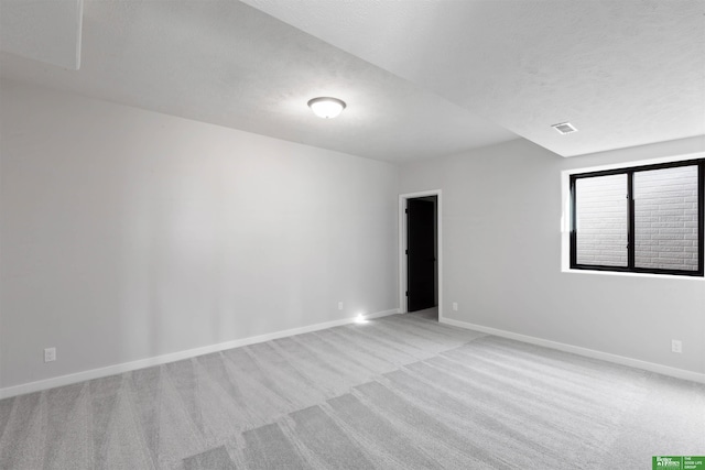 spare room featuring light carpet and a textured ceiling