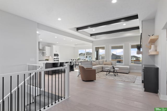 living room featuring a raised ceiling, sink, and light wood-type flooring