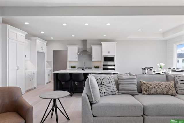 living room with light wood-type flooring and a tray ceiling