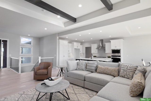 living room with beamed ceiling, sink, and light hardwood / wood-style flooring