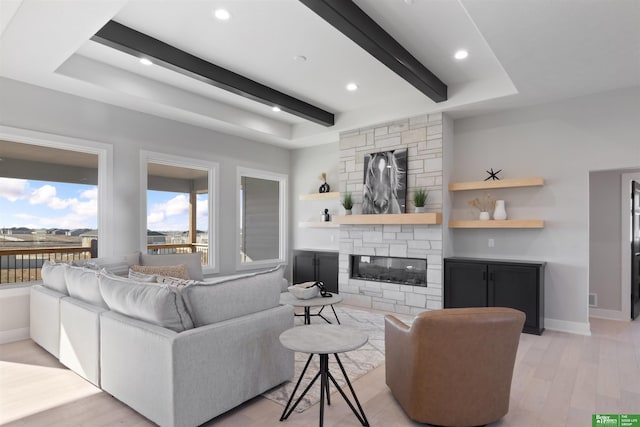 living room featuring beamed ceiling, light wood-type flooring, and a fireplace