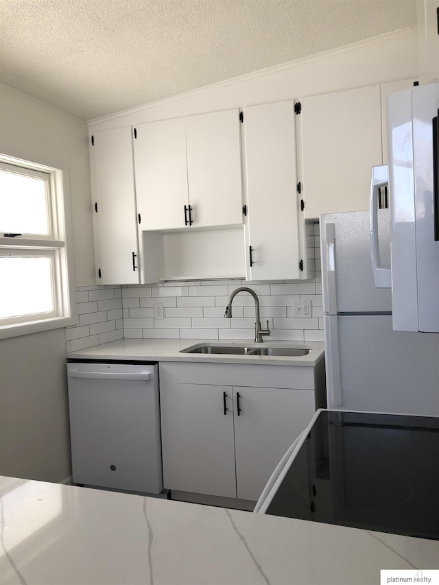 kitchen featuring white appliances, a sink, white cabinetry, light countertops, and backsplash