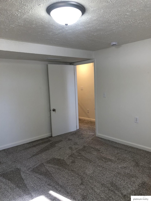 carpeted empty room with a textured ceiling and baseboards