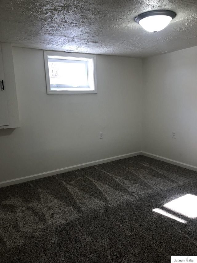 empty room featuring a textured ceiling, carpet flooring, and baseboards