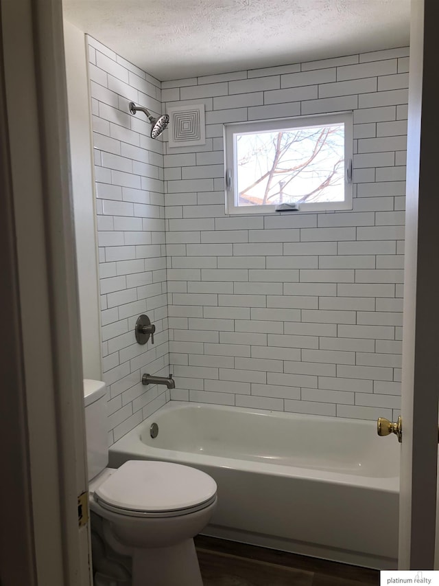 bathroom with shower / bathtub combination, a textured ceiling, and toilet