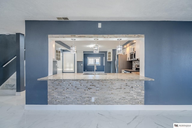 kitchen featuring sink, white cabinets, hanging light fixtures, kitchen peninsula, and stainless steel appliances