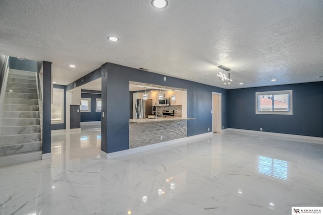 unfurnished living room featuring sink and a textured ceiling