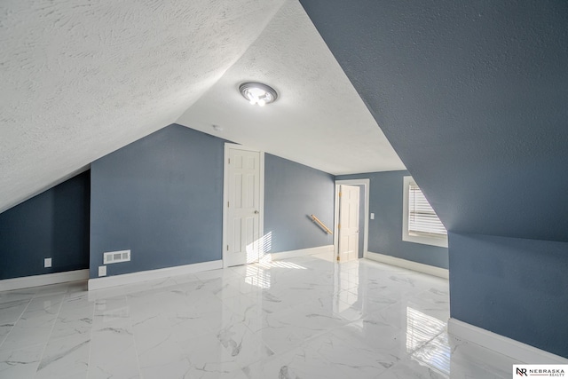 bonus room with lofted ceiling and a textured ceiling