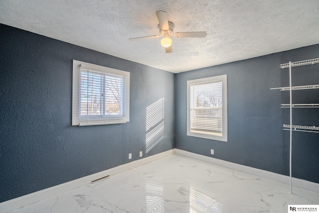 spare room featuring ceiling fan, a wealth of natural light, and a textured ceiling