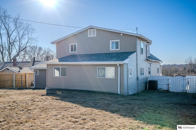 back of property featuring a lawn and central air condition unit