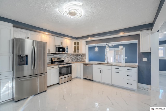 kitchen with pendant lighting, sink, white cabinets, and appliances with stainless steel finishes