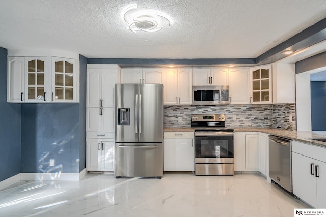 kitchen featuring white cabinets, decorative backsplash, light stone counters, stainless steel appliances, and a textured ceiling