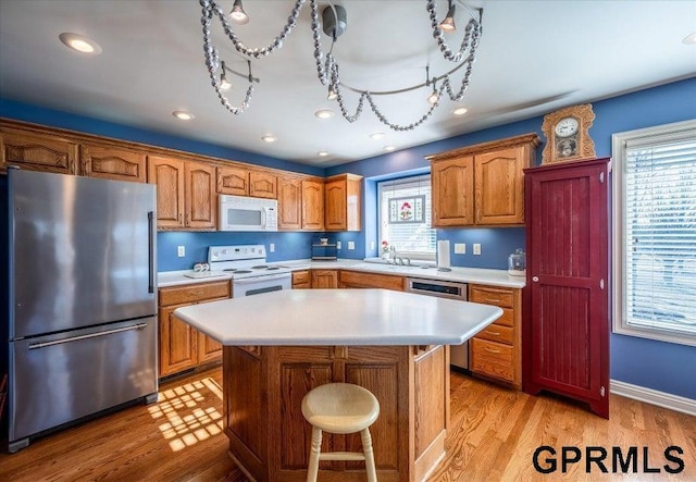 kitchen featuring a healthy amount of sunlight, appliances with stainless steel finishes, light hardwood / wood-style floors, and a kitchen island