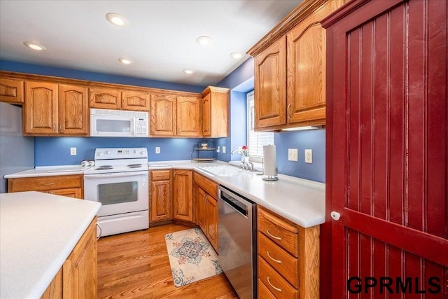 kitchen with stainless steel appliances, sink, and light hardwood / wood-style flooring