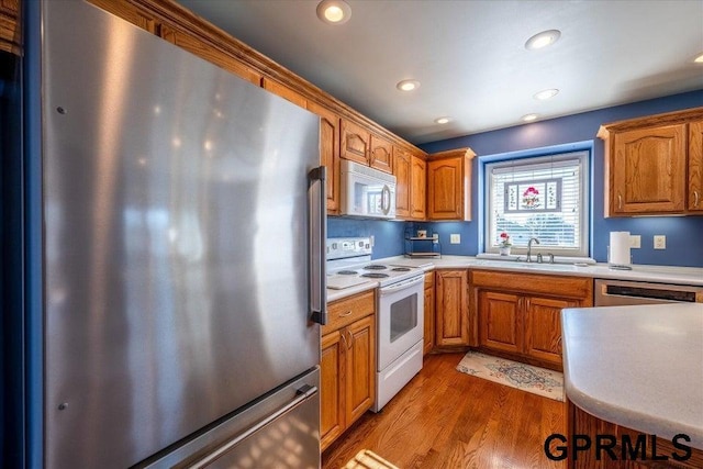 kitchen with stainless steel appliances, sink, and wood-type flooring