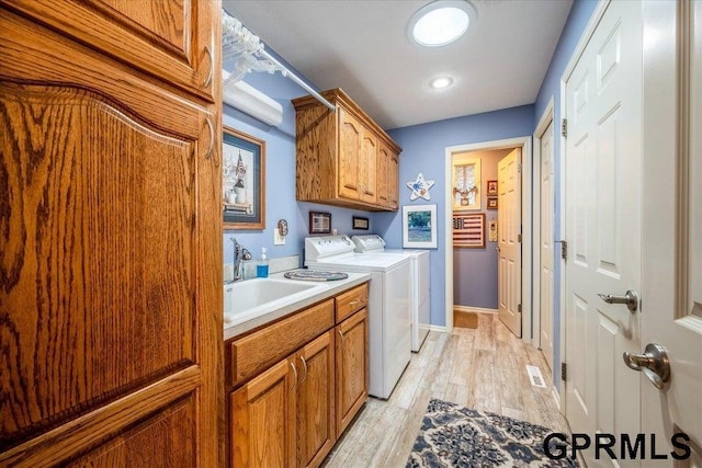 washroom featuring sink, cabinets, washing machine and clothes dryer, and light wood-type flooring