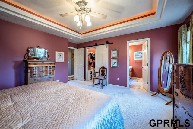 bedroom with light carpet, ensuite bathroom, a raised ceiling, and a barn door