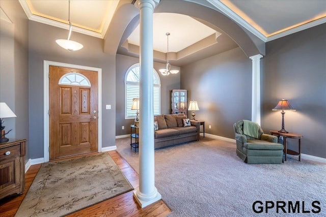 entrance foyer featuring ornamental molding, carpet flooring, and ornate columns