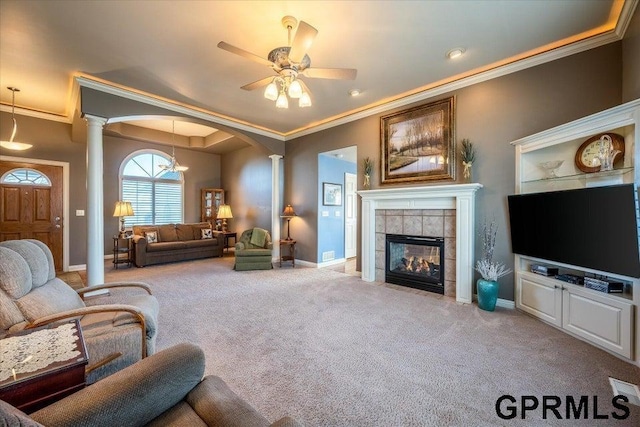 carpeted living room featuring ornate columns, a tile fireplace, ornamental molding, and ceiling fan